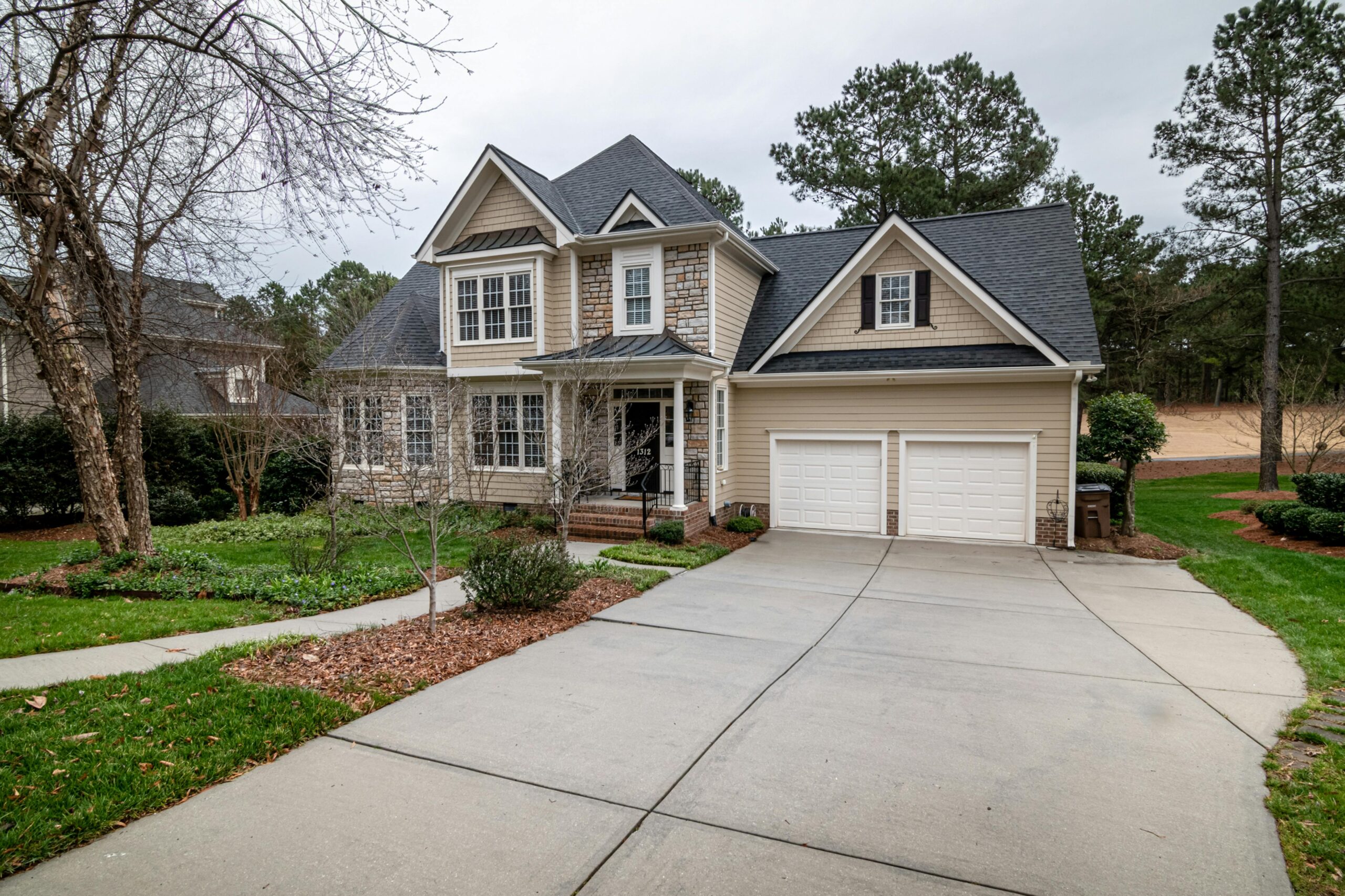 Charming suburban home featuring a two-car garage, manicured lawn, and inviting entrance.